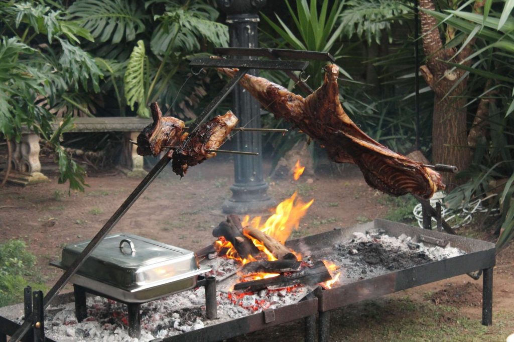 Whole lamb roasting on the spit over open coals at a Pedros Asado catering event